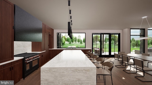 kitchen featuring a center island, light wood-type flooring, wall chimney range hood, double oven range, and a breakfast bar area