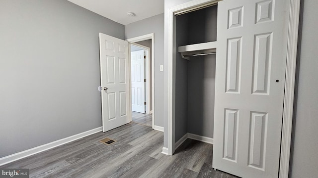 unfurnished bedroom with dark wood-type flooring and a closet