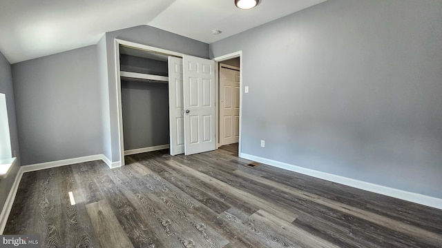 unfurnished bedroom featuring a closet, dark hardwood / wood-style floors, and vaulted ceiling