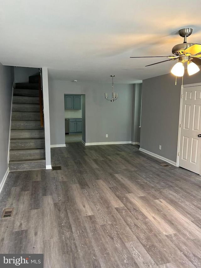 unfurnished living room featuring dark wood-type flooring and ceiling fan with notable chandelier