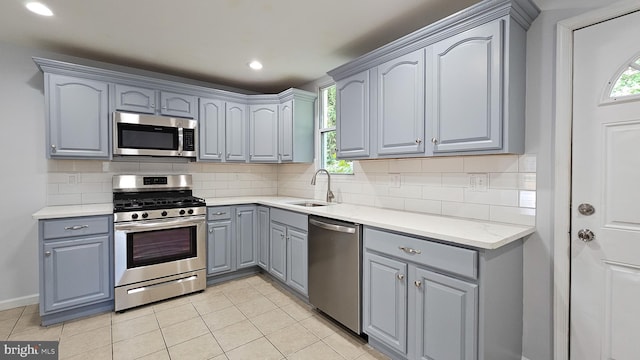 kitchen with appliances with stainless steel finishes, sink, tasteful backsplash, light tile patterned floors, and gray cabinets