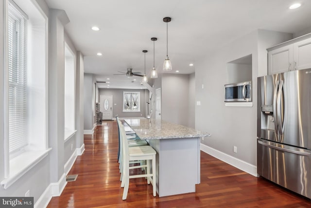 kitchen with a center island, a breakfast bar area, hanging light fixtures, and appliances with stainless steel finishes