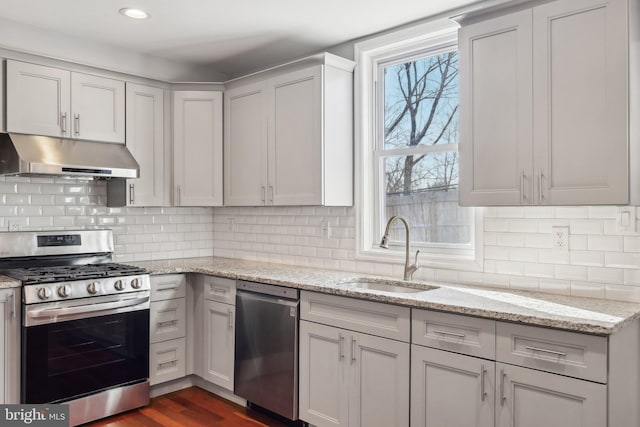 kitchen featuring sink, dark wood-type flooring, light stone countertops, decorative backsplash, and stainless steel appliances