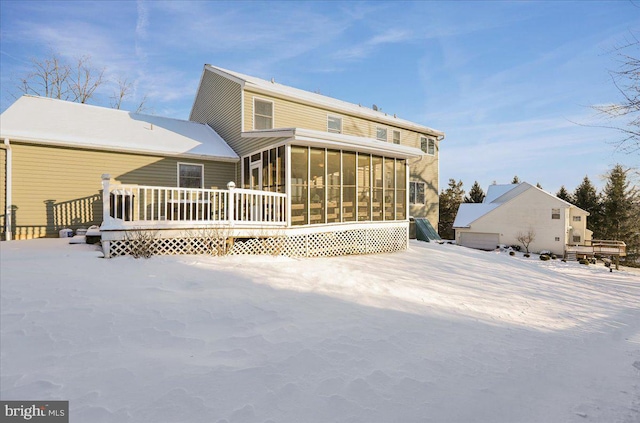 snow covered property with a wooden deck and a sunroom