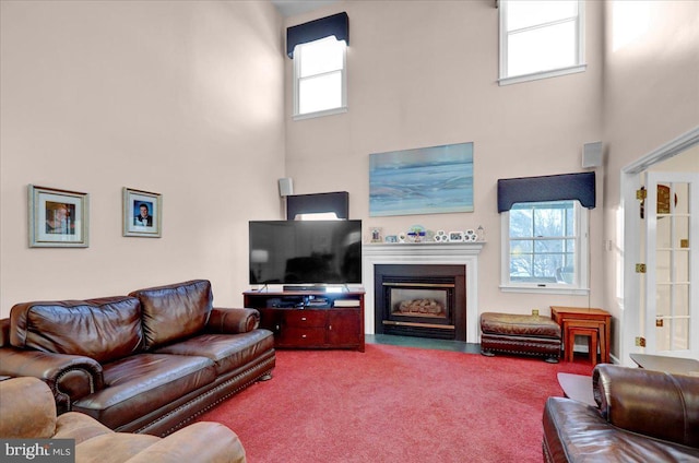 living room featuring carpet floors, a towering ceiling, and plenty of natural light