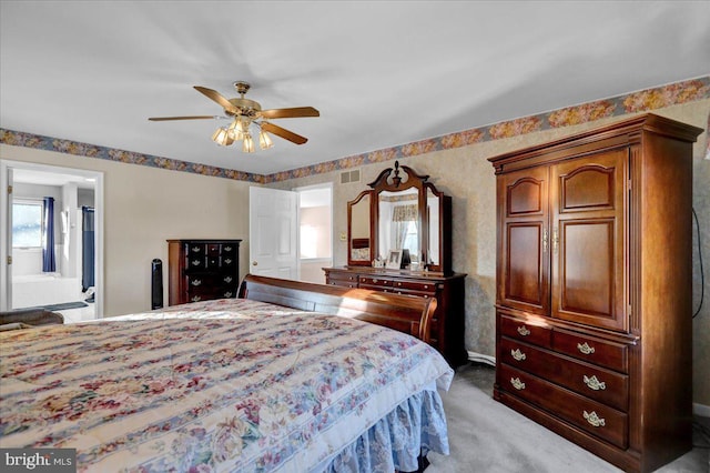 carpeted bedroom featuring ceiling fan and ensuite bath