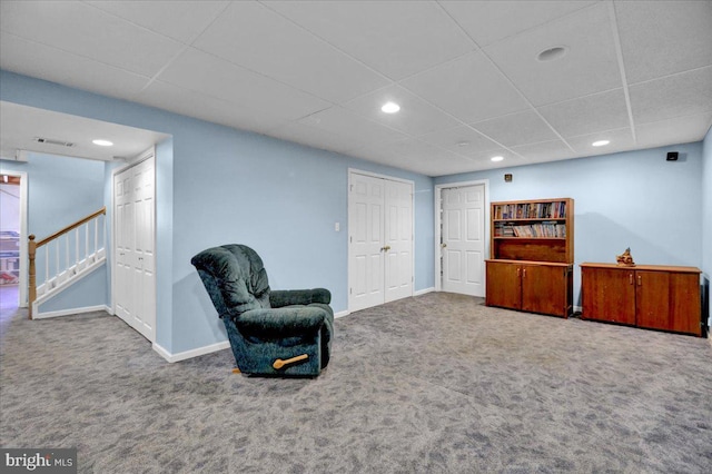 sitting room with a paneled ceiling and carpet floors