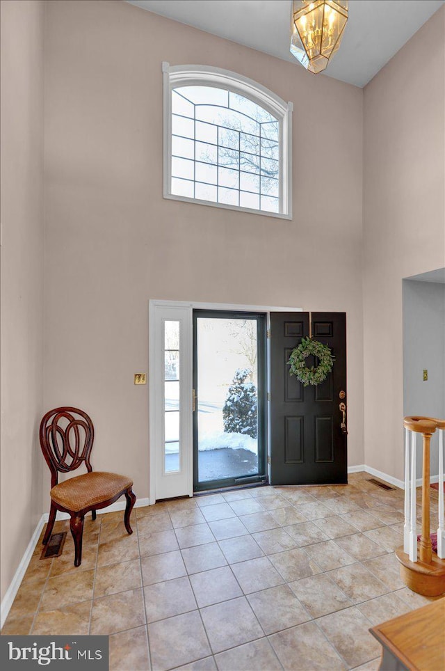 tiled entrance foyer with a notable chandelier and a towering ceiling