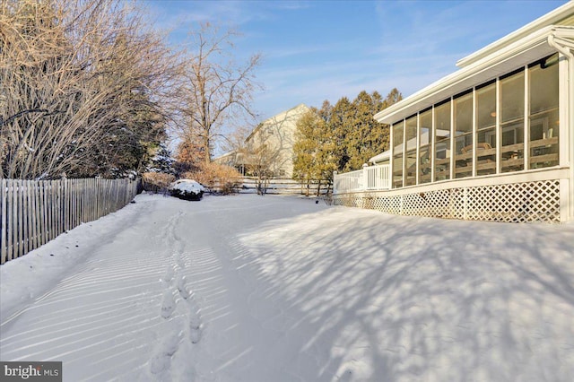 yard layered in snow with a sunroom