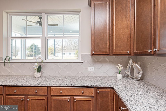 kitchen featuring decorative backsplash, light stone countertops, and ceiling fan