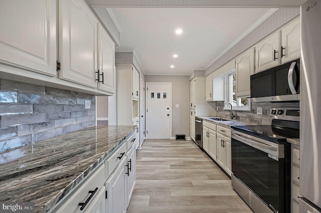 kitchen featuring sink, dark stone countertops, ornamental molding, appliances with stainless steel finishes, and white cabinets