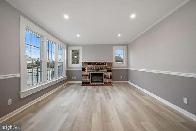 unfurnished living room featuring crown molding, a fireplace, and light wood-type flooring