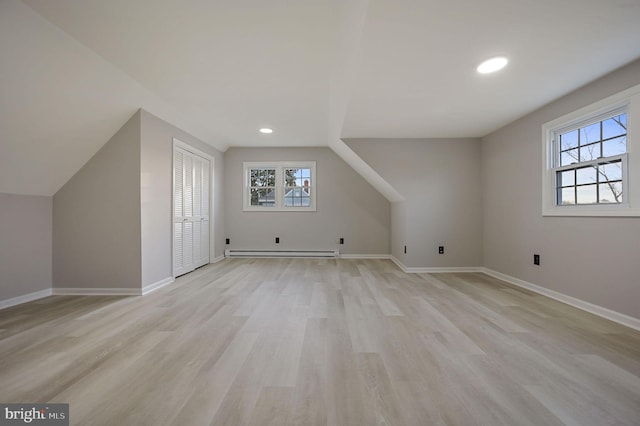 bonus room with vaulted ceiling, plenty of natural light, a baseboard heating unit, and light wood-type flooring