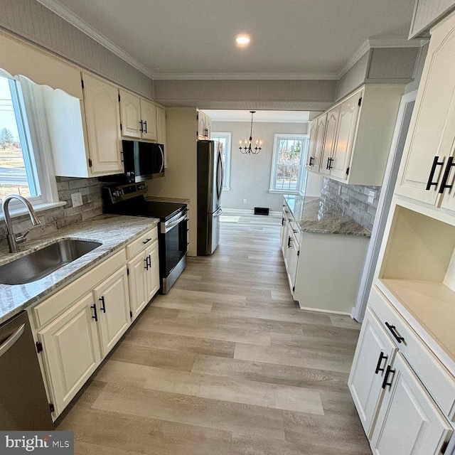 kitchen featuring pendant lighting, sink, white cabinetry, stainless steel appliances, and a notable chandelier