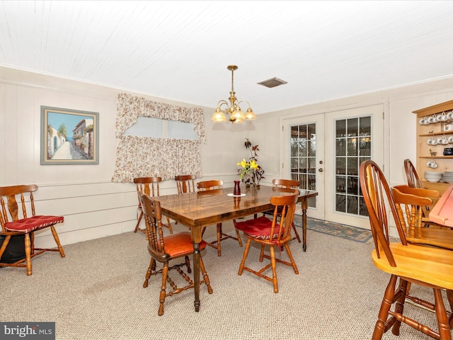 dining room with light carpet, french doors, and an inviting chandelier