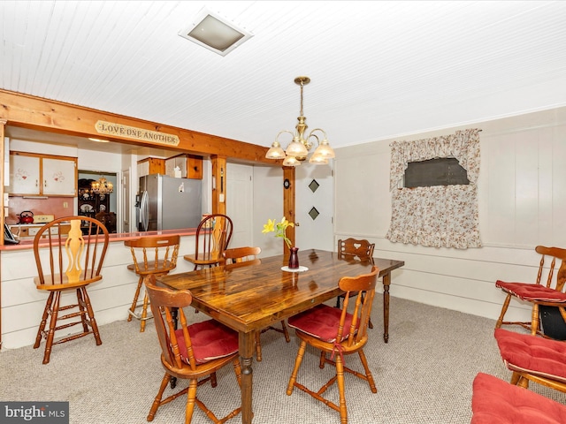 dining area featuring light carpet and an inviting chandelier