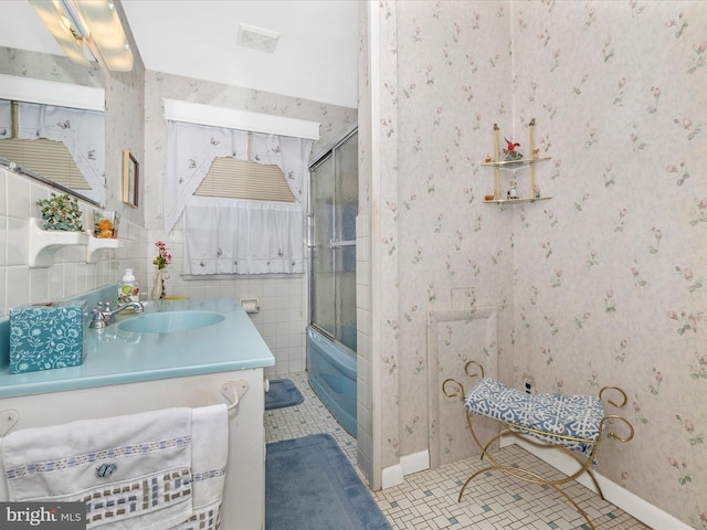 bathroom featuring vanity, combined bath / shower with glass door, tile patterned flooring, and tile walls