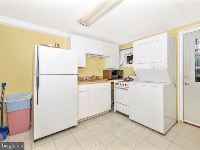 kitchen featuring white cabinetry, sink, white appliances, and stacked washing maching and dryer