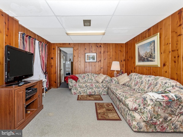 carpeted living room with a paneled ceiling and wood walls