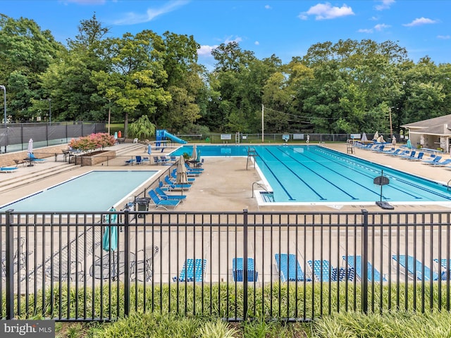 view of swimming pool with a water slide and a patio