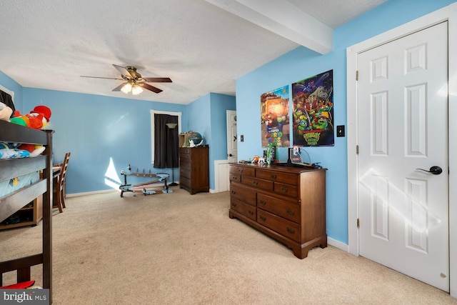 carpeted bedroom with beam ceiling, ceiling fan, and a textured ceiling