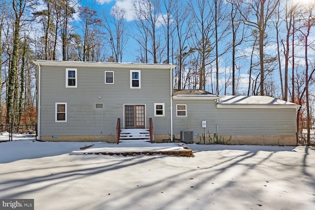 snow covered rear of property featuring central AC unit