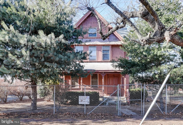 view of front of property featuring a fenced front yard, covered porch, and a gate