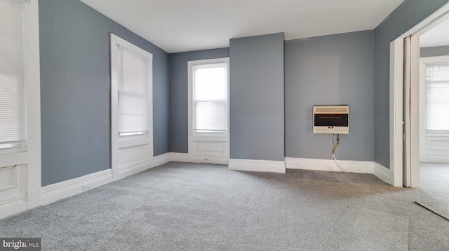 carpeted spare room with heating unit and baseboards