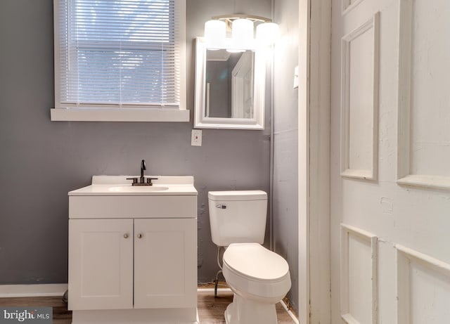 half bathroom featuring vanity, toilet, and wood finished floors