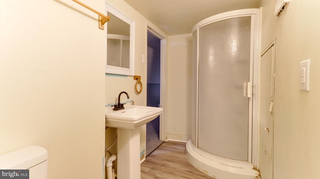 full bath featuring toilet, wood finished floors, a stall shower, and a sink