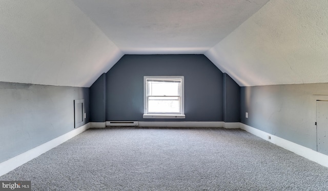 additional living space featuring a textured ceiling, carpet floors, a baseboard radiator, baseboards, and vaulted ceiling