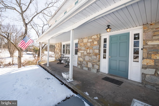 snow covered property entrance featuring covered porch