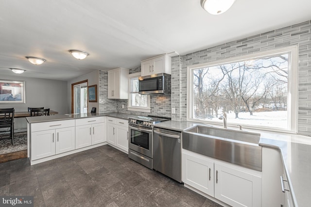 kitchen with appliances with stainless steel finishes, tasteful backsplash, sink, white cabinets, and kitchen peninsula