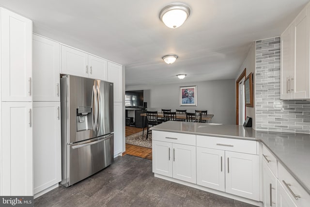 kitchen with stainless steel fridge with ice dispenser, decorative backsplash, kitchen peninsula, and white cabinets