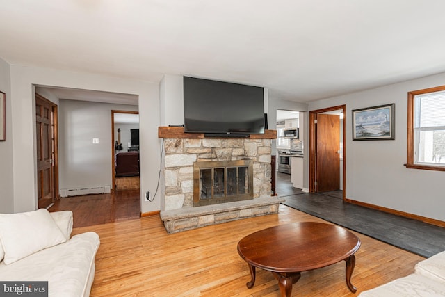 living room featuring a fireplace, baseboard heating, and light hardwood / wood-style flooring