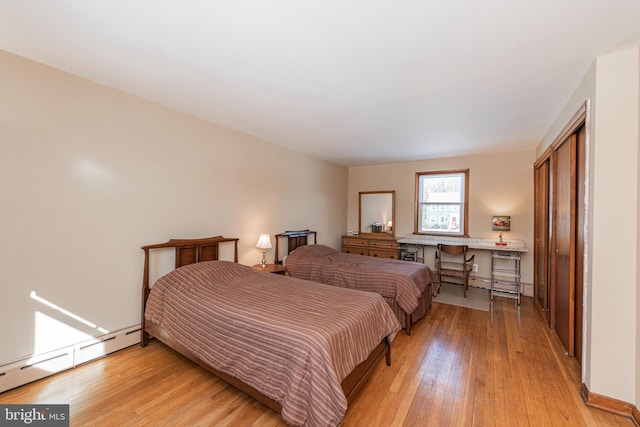 bedroom with a baseboard radiator, light wood-type flooring, and a closet