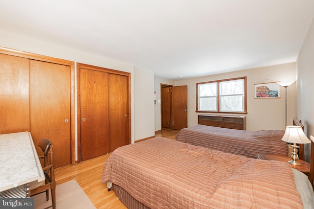 bedroom featuring two closets and light wood-type flooring