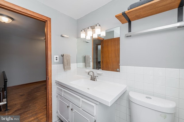 bathroom featuring vanity, toilet, hardwood / wood-style floors, and tile walls