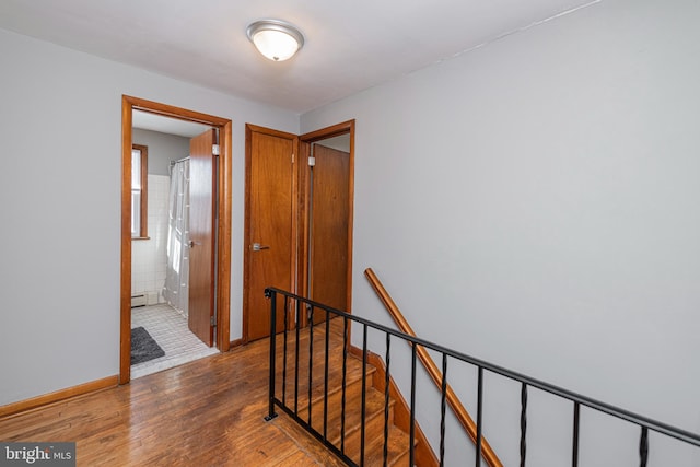 corridor with a baseboard heating unit and hardwood / wood-style flooring