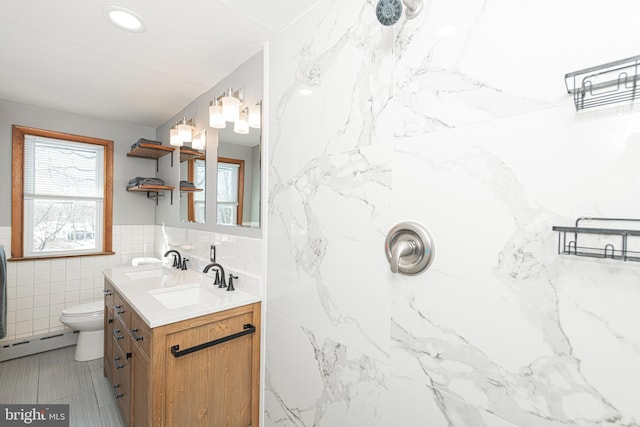 bathroom with a baseboard radiator, tile walls, vanity, and toilet