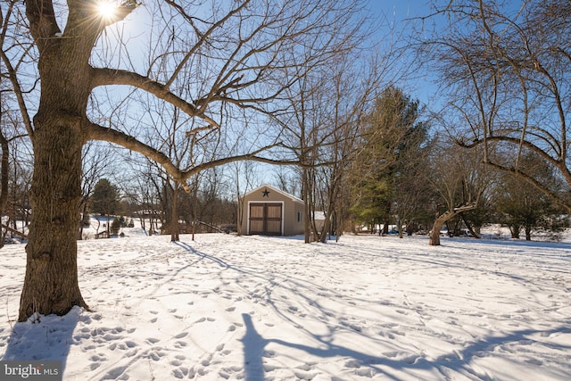 yard layered in snow with an outbuilding and a garage