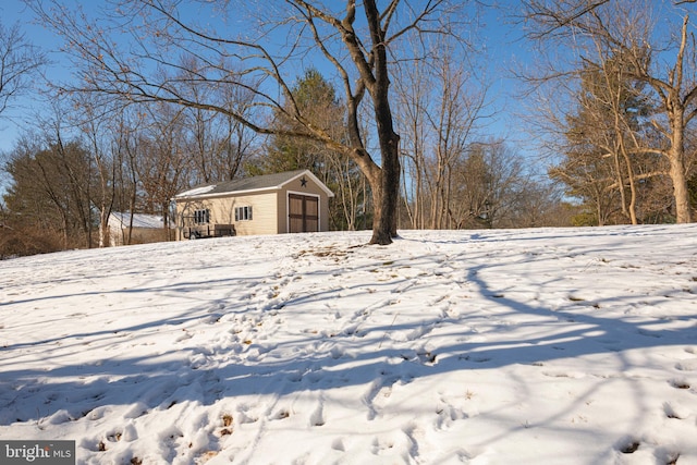 yard covered in snow featuring a garage and an outdoor structure