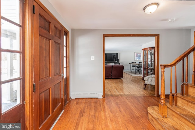 foyer entrance with a baseboard radiator, a wealth of natural light, and light hardwood / wood-style flooring