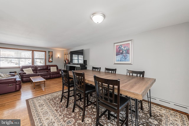 dining room with wood-type flooring and a baseboard heating unit