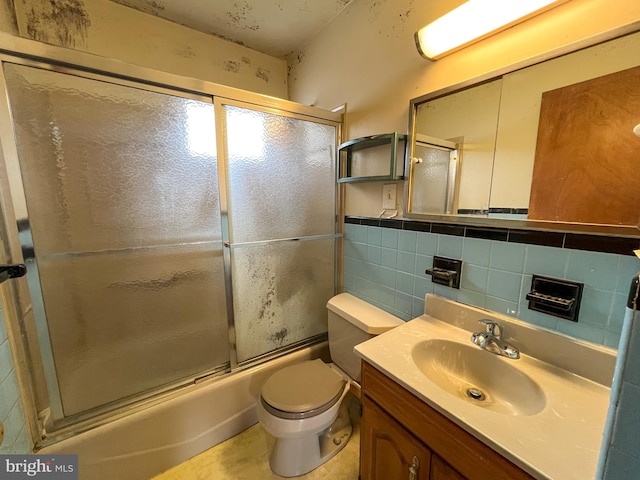 full bathroom featuring toilet, vanity, tile walls, backsplash, and combined bath / shower with glass door