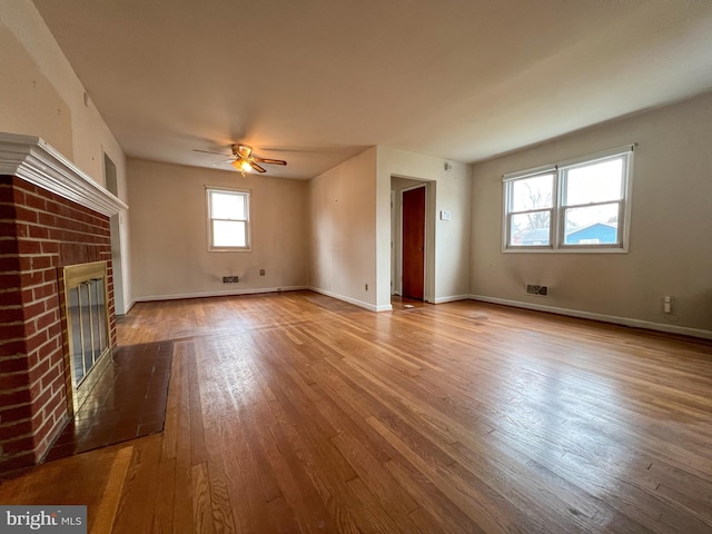 unfurnished living room featuring a brick fireplace, ceiling fan, and light wood-type flooring