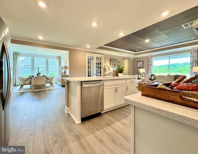 kitchen featuring appliances with stainless steel finishes, white cabinetry, a raised ceiling, a kitchen island with sink, and light hardwood / wood-style flooring