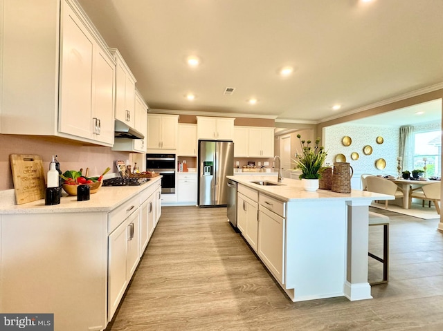 kitchen featuring white cabinets, appliances with stainless steel finishes, light hardwood / wood-style flooring, sink, and a center island with sink