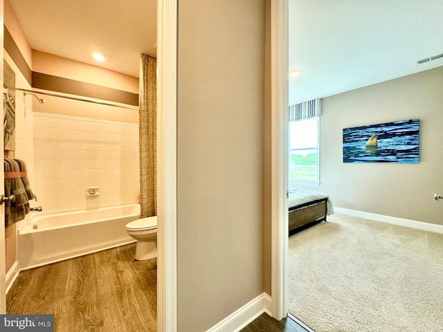 bathroom featuring toilet, hardwood / wood-style flooring, and shower / tub combo with curtain