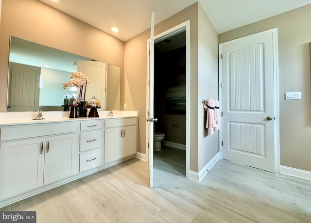 bathroom with hardwood / wood-style flooring, toilet, and vanity